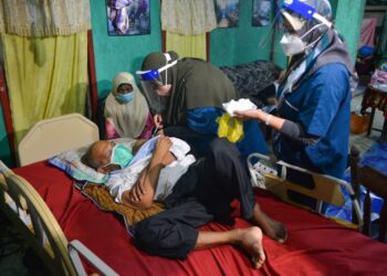 PETUGAS pusat pemberian vaksin (PPV) Universiti Sultan Zainal Abidin (Unisza) memberikan suntikan vaksin Covid-19 kepada Rozelan Awang, 54, yang terlantar akibat strok di Kampung Teluk Pasu di Kuala Terengganu, hari ini. - PUQTRA HAIRRY ROSLI