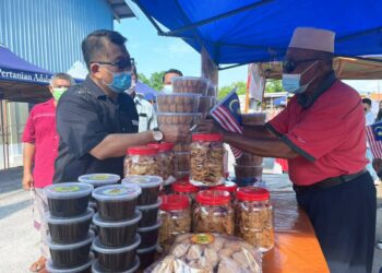 MUHAMMAD JAILANI Khamis memberikan Jalur Gemilang kepada salah seorang peniaga di Program Pasar Segar Terkawal di Japerun Rembia, Melaka. - UTUSAN/DIYANATUL ATIQAH ZAKARYA