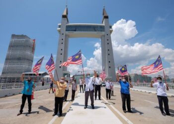 TUN Ahmad Faisal Tun Abdul Razak (tengah) mengibarkan Jalur Gemilang di jambatan angkat (drawbridge) di Kuala Terengganu, hari ini.