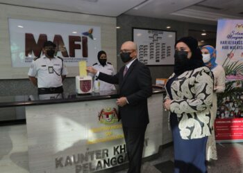 RONALD Kiandee mengimbas kad perakam waktu di pejabatnya di Wisma Tani selepas selesai istiadat mengangkat sumpah.- FOTO MAFI