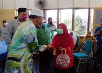 IDRIS Ahmad (kiri) menyampaikan bantuan kepada mangsa banjir di Matang, dekat Bukit Gantang. - UTUSAN/WAT KAMAL ABAS