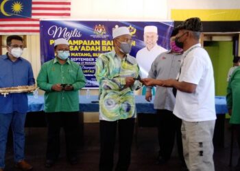 IDRIS Ahmad (kiri) menyampaikan bantuan kepada mangsa banjir di Matang, dekat Bukit Gantang. - UTUSAN/WAT KAMAL ABAS