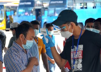 SEORANG petugas sukarelawan mengimbas suhu salah seorang pekerja asing sebelum dibenarkan memasuki dewan untuk divaksinasi di PPV Mount Austin di AICC di Johor. - UTUSAN/RAJA JAAFAR ALI