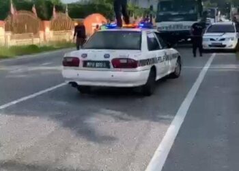 TANGKAP layar seorang lelaki berdiri di atas kereta peronda polis sambil menghayun sabit di hadapan Balai Polis Gopeng, Perak, tular di media sosial.- UTUSAN/MEDIA SOSIAL