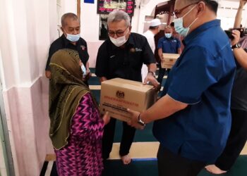 MOHD. REDZUAN Md. Yusof (tengah) menyampaikan kit makanan kepada golongan asnaf di Masjid Al-Qaniteen, Kampung Tanjung Rimau, Gadek, Melaka. - UTUSAN/AMRAN MULUP
