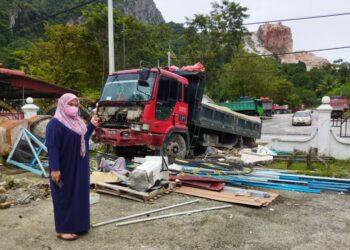 AISHAH Masri menunjukkan sebuah lori yang dipenuhi muatan batu merempuh pagar batu rumahnya di Kampung Bawah Gunung, Baling hari ini. - UTUSAN/NORLIA RAMLI