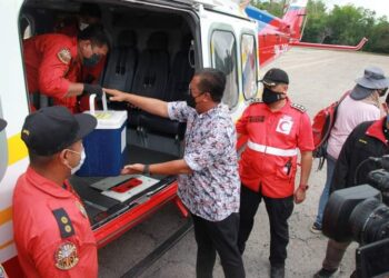 ABDUL RAHMAN Mohamad (tengah) membantu mengangkat dos vaksin Cansino untuk dibawa dengan helikopter ke tiga buah penempatan Orang Asli Hulu Jelai di Kuala Lipis, Pahang. - UTUSAN/HARIS FADILAH AHMAD