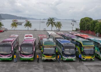 BEBERAPA petugas melakukan sanitasi ke atas bas persiaran di Pekan Rabu, Langkawi hari ini. - UTUSAN/SHAHIR NOORDIN