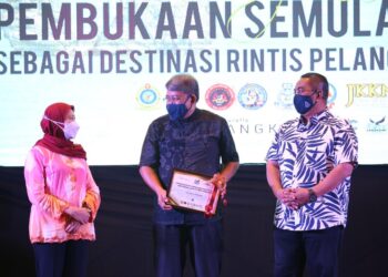 NANCY  (kiri) memperkatakan sesuatu kepada salah seorang penggiat industri yang menerima sijil MySafe Langkawi sambil diperhatikan oleh Muhammad Sanusi Md. Nor (kanan) pada majlis Pelancaran Inisiatif Pembukaan Semula Sektor Pelancongan di Langkawi malam ini.