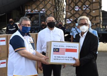 SAIFUDDIN ABDULLAH (kiri) menyerahkan simbolik bantuan kepada Hermono sambil disaksikan Hishammuddin Hussein di Subang, Selangor hari ini. – Ihsan Wisma Putra