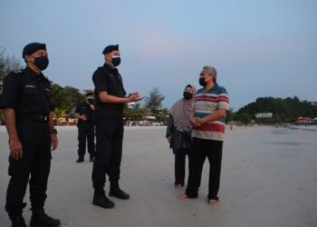 SHARIMAN Ashari memberi nasihat kepada pengunjung mengenai pematuhan SOP 
di Pantai Chenang, Langkawi petang ini.