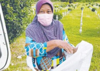 FARIDAH Said melakukan persiapan dengan memakai pakaian perlindungan diri (PPE) sebelum memguruskan jenazah pesakit Covid-19 di Merbok, Sungai Petani, Kedah. - UTUSAN/NUR SYAZWANA MANSOR
