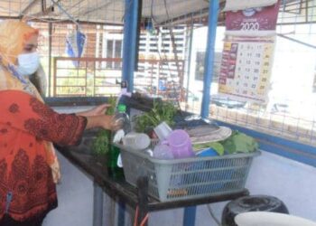 NORAZLINA Arshad membasuh sayur-sayuran menggunakan bekalan air SADA yang kembali pulih di gerainya di Kampung Pauh, Yan hari ini. - UTUSAN/OTHMAN YAHAYA