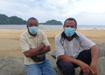 MOHD. Ibrahim (kiri) dan Mahadi Ibrahim menunggu Mohd. Noor Mamat yang dikhuatiri lemas di perairan Kuala Dungun di Dungun, hari ini. - NIK NUR IZZATUL HAZWANI NIK ADNAN