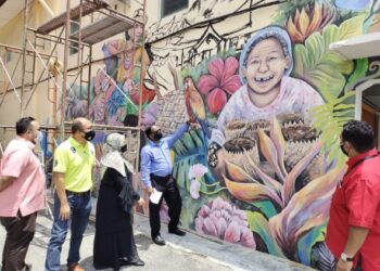 S. Veerapan (dua dari kanan) dan Suhaiza (tiga dari kiri) melihat projek lukisan mural yang terletak di sempadan Tampin dan Pulau Sebang, di Tampin, kelmarin.-UTUSAN/NOR AINNA HAMZAH.
