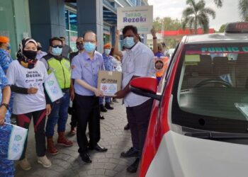 TONG Sing Chuang (depan, kiri) menyampaikan kotak makanan kepada seorang pemandu teksi di Menara Perkeso Johor, di Johor Bahru. -UTUSAN/KHAIRUL MOHD ALI