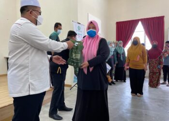 AHMAD Marzuk Shaary (kiri) menyampaikan agihan daging segar kepada penduduk Penempatan Semula Nelayan Tok Bali, di Pasir Puteh, hari ini. - UTUSAN/TOREK SULONG