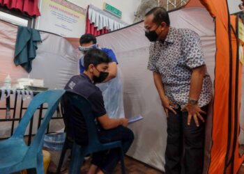 AHMAD Samsuri Mokhtar (kanan) beramah mesra dengan penerima vaksin remaja di Sekolah Menengah Kebangsaan (SMK) Pengkalan Berangan di Marang hari ini. - PUQTRA HAIRRY ROSLI