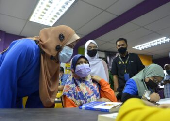 NOLEE Ashilin Mohamed Radzi (kiri) beramah mesra dengan pelajar pada program penyerahan sumbangan peranti mudah alih kepada Perpustakaan Komuniti PPR Seri Kepayang di Ipoh hari ini. - UTUSAN/ZULFACHRI ZULKIFLI