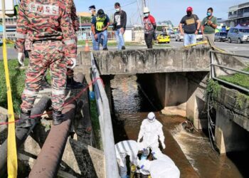 Anggota bomba mengeluarkan mayat mangsa yang terkena renjatan elektrik dari longkang di simpang masuk Pekan Batu 8, Sandakan, pagi tadi.-IHSAN Bomba