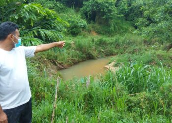 MOHAMAD Nasir Mohd. Razali menunjukkan keadaan Sungai Ngor yang ditambak sehingga menjadi sempit dan mengakibatkan banjir kilat di Kampung Ngor, Kuala Kangsar.  - UTUSAN