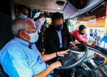 MAHDZIR Khalid diberi penerangan mengenai pemandu bas oleh Pengarah Pembangunan Strategik Pelanggan Scania, Idros Puteh pada Majlis Penyerahan Bas Baharu Mara Liner di Bengkel Mara Liner Kuala Nerang, Padang Terap hari ini. - UTUSAN/ZAID MOHD. NOOR
