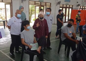 NANCY Shukri (kanan) bercakap kepada seorang pelajar di pusat pemberian vaksin di SMK Simunjan.