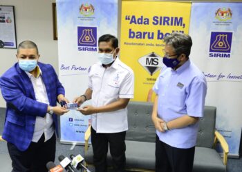 HISHAMUDDIN Abdullah (kiri) menyerahkan kepingan emas Mahkmur Gold kepada Hamdan Hussin (tengah) selepas lawatan ke kilang pemprossan emas Makmur Gold, di pejabat SIRIM, Jalan Pintasan Kuantan-Kemaman di Kuantan, Pahang. - UTUSAN/SHAIKH AHMAD RAZIF