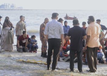 MUHAMMAD Miqdam Bahtiar (duduk, empat dari kiri) ketika anggota penyelamat memberikan bantuan pernafasan kepada anaknya yang ditemukam lemas di Pantai Seaview, Tanjung Gemuk, Port Dickson, petang tadi.-UTUSAN/MOHD. SHAHJEHAN MAAMIN.