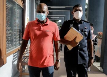 KOPERAL S. P. Varathraju Pillai (kiri) diiringi pegawai polis masuk ke Mahkamah Majistret Ipoh bagi menghadapi pertuduhan membuat laporan polis palsu hari ini. - UTUSAN/ASLIZA MUSA
