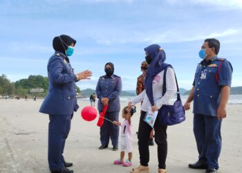 SAYANI Saidon (kiri) memberi nasihat kepada pengunjung untuk menjaga keselamatan sekiranya melakukan aktiviti air di Pantai Chenang, Langkawi, hari ini. - UTUSAN/NUR AMALINA AZMAN