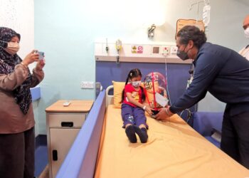 KHAIRY Jamaluddin menyampaikan cenderahati kepada Nurmusfirah Musa, 7, ketika melawat bilik Wad Kanak-Kanak Pusat Perubatan Mawar di Seremban hari ini.-UTUSAN/MOHD. SHAHJEHAN MAAMIN.
