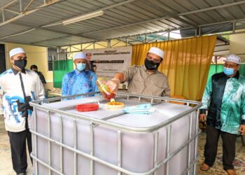MOHD. Akmal Kamarudin (dua dari kanan) menuang minyak masak terpakai ke dalam tong pada program O-waste di Kampar hari ini. - UTUSAN/MOHAMAD HAFIZI MOHD. SAID