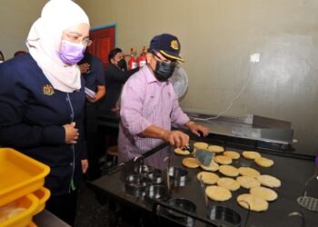 AHMAD Hamzah (kanan) mencuba menyiapkan roti canai ketika melakukan lawatan kerja di Projek Pemprosesan Makanan Sejuk Beku, Nazla Enterprise di Felda Pasak, Kota Tinggi di Johor. -UTUSAN/RAJA JAAFAR ALI