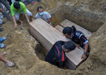 CHE Mohd. Humaizi Che Jemani (kanan) menurunkan jenazah anaknya, Nurul Hasha Humaira untuk dikebumikan dalam satu liang lahad bersama dua anak saudaranya di Tanah Perkuburan Islam Kampung Losong Panglima Perang di Kuala Terengganu, hari ini. - UTUSAN/PUQTRA HAIRRY ROSLI
