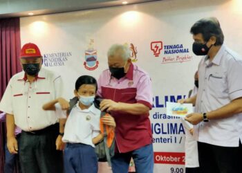 BUNG Moktar (dua kanan) menyampaikan sumbangan kelengkapan persekolahan kepada salah seorang penerima dalam majlis penyerahan sumbangan ceria ke sekolah di Kinabatangan semalam.