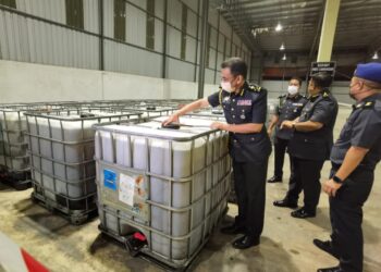 AZMAN Adam memeriksa minyak masak bersubsidi yang dirampas di stor eksibit di Krubong, Melaka malam tadi. - UTUSAN/DIYANATUL ATIQAH ZAKARYA
