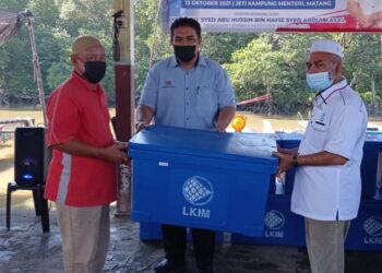 SYED Abu Hussin Hafiz Syed Abdul Fasal (dua dari kanan) menyerahkan kotak ikan kepada ahli PNK Matang di Kampung Menteri di Kuala Sepetang dekat Bukit Gantang hari ini. - UTUSAN/WAT KAMAL ABAS