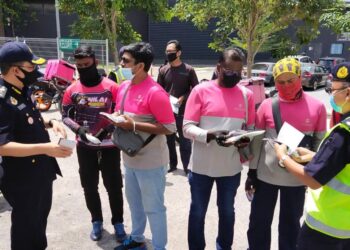 AZRIN Borhan (kiri) memberi advokasi kepada penunggang motosikal p-hailing bagi memberi kesedaran tentang peraturan lalu-lintas dekat Nilai di sini semalam.-UTUSAN/NOR SHAFAWATI YUP.