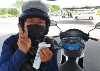 NUR Fathen Amirah Kosmani yang menunggang motosikal dari Batu Pahat gembira menunjukkan keputusan ujian RTK negatif sebelum dia dibenarkan memasuki kampus di UTM, Skudai di Johor Bahru. -UTUSAN/RAJA JAAFAR ALI