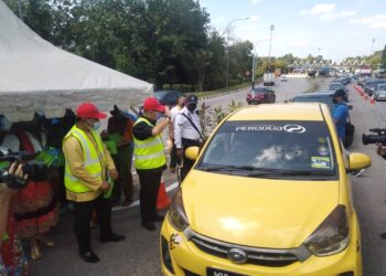 MUHAMMAD Jailani Khamis (dua dari kiri) menyambut ketibaan pelancong di Plaza Tol Ayer Keroh, Melaka. - UTUSAN/MUHAMMAD SHAHIZAM TAZALI