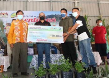 RONALD Kiandee (dua kiri) menyampaikan bantuan Program Kebuniti kepada wakil peserta sempena Program Sentuhan Kasih Tani di Telupid hari ini.