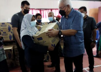 HAMZAH Zainuddin (kanan) menyampaikan kotak makanan kepada penduduk pada program di Kubu Gajah dekat Larut hari ini. - UTUSAN/WAT KAMAL ABAS