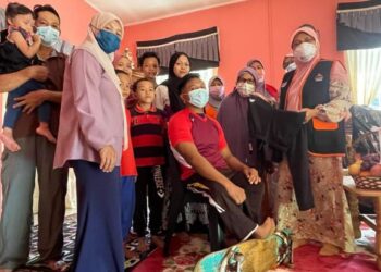 HAFIDZAH Mustakim (kanan) menyampaikan sumbangan pakaian sukan dan wang kepada Ahmad Shahmin Mohd. Kadri ketika berkunjung ke rumah atlet OKU tersebut di Kampung Alor Hijau, Selising, Pasir Puteh, semalam. – UTUSAN/TOREK SULONG