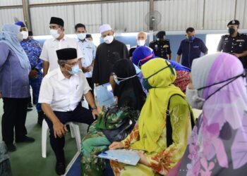 WAN Rosdy Wan Ismail menyantuni sebahagian penerima suratan hak milik tanah Taman Sepakat selepas selasai menyerahkan suratan hak milik tersebut kepada 81 penerima di Dewan Taman Sepakat di Kuantan, Pahang. - UTUSAN/SHAIKH AHMAD RAZIF
