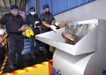 AZMAN Adam (kanan) melupuskan kasut tiruan yang dirampas sebelum ini selepas sidang akhbar Pelupusan Eksibit Mega KPDNHEP di Kompleks Penyimpanan Bahagian Penguat Kuasa KPDNHEP di Nilai, Seremban hari ini. - UTUSAN/MOHD. SHAHJEHAN MAAMIN