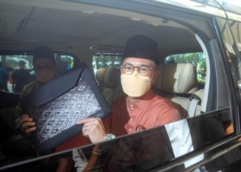 TENGKU Zafrul Tengku Abdul Aziz menunjukkan beg yang berisi buku laporan Belanjawan 2022 ketika keluar dari Kompleks Kementerian Kewangan menuju ke Bangunan Parlimen bagi membentangkan belanjawan tersebut. - UTUSAN/FAISOL MUSTAFA