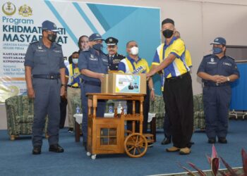 SAARANI Mohamad (dua dari kanan) menyerahkan kotak makanan kepada wakil penduduk pada Program Khidmat Bakti Masyarakat JKDM Perak di Dewan Merdeka Lenggong hari ini. - UTUSAN/ZULFACHRI ZULKIFLI