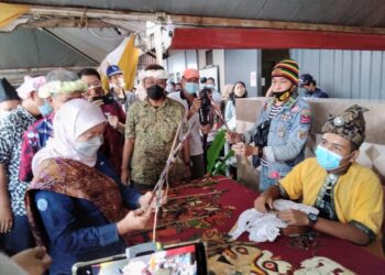 NANCY Shukri (kiri) ditunjukkan cara permainan wayang kulit ketika meninjau gerai pameran di Jeti Pasar Terapung, Pangkalan Datu, Kota Bharu hari ini. - UTUSAN/ROHANA MOHD. NAWI