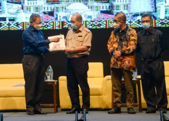 MUSTAPHA Mohamed (kiri) menyerahkan buku RMK-12 kepada Hajiji Noor (dua kiri) sambil disaksikan oleh Maximus Ongkili (dua kanan) selepas sesi libat urus pasca RMK-12, di Kota Kinabalu hari ini. - IHSAN JABATAN KETUA MENTERI